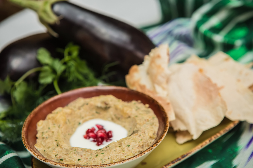 Traditional arabian eggplant dip baba ganoush with herbs and smoked paprika on a wooden background